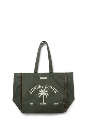 Sac cabas vert foncé avec le texte "SUNSET LOVER the beach club" et un motif de palmier, doté de deux anses et de coutures latérales à franges.