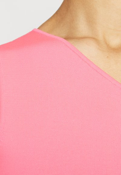 Tett, teksturert rosa topp med V-halsdesign. Stoffet har et ribbestrikket mønster som gir økt visuell interesse og taktil kvalitet.