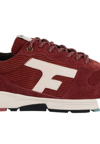 Sneaker rossa in suede con texture a righe, accentuato da un logo bianco e una suola a contrasto nera e teal. Presenta lacci rotondi e occhielli.