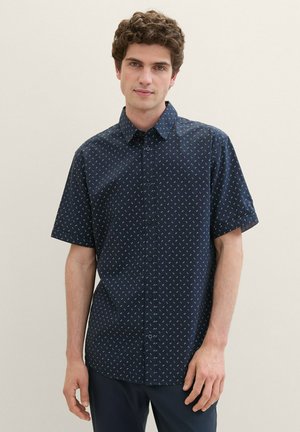 Kurzarmhemd in Marineblau mit Button-Down-Kragen, das ein kleines geometrisches Muster in hellen Farben und einen geraden Saum aufweist.