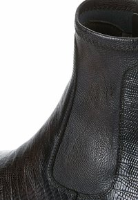 Černá kožená kotníková obuv s texturovaným povrchem, elastickými bočními panely a hladkým šitím podél svršku pro elegantní design.