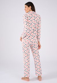Fleece pyjama set met een roze achtergrond en een all-over print van hartjes in verschillende tinten roze en grijs. Lange mouwen top en broek.