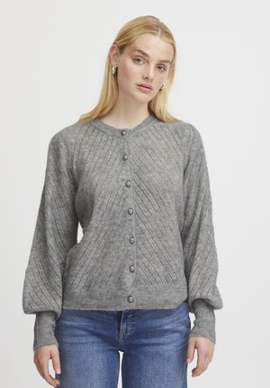 Grauer gestrickter Cardigan mit einem gerippten Kragen, diagonalem Strukturmuster, Knöpfen an der Vorderseite und ballonförmigen Ärmeln, kombiniert mit blauen Jeans.