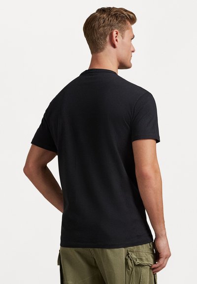 Μαύρη βαμβακερή μπλούζα με στρογγυλή λαιμόκοψη. Κοντά μανίκια και κλασική εφαρμογή. Η πλάτη έχει σχέδιο χωρίς ραφές και χωρίς γραφικά ή μοτίβα.