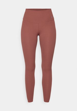 Tights in a reddish-brown color made from stretchy fabric. Features a high waistband and a small branded logo near the hip.