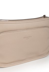 Borsa a tracolla in pelle beige con una texture liscia, dotata di una tasca frontale, cuciture raffinate e logo embossato "HEXAGONA PARIS".