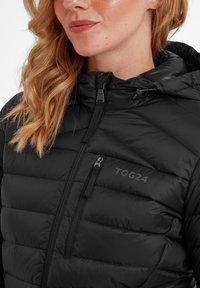 Black padded jacket with a hood, featuring a zippered front, diagonal quilted texture, and subtle branding on the chest.