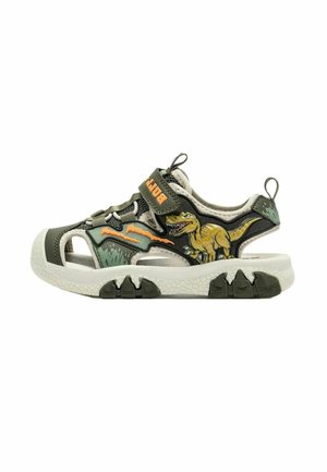 Sandalo verde e beige per bambini con grafica di dinosauro e segni di artigli arancioni sul lato, con cinturino in velcro e suola spessa e strutturata.