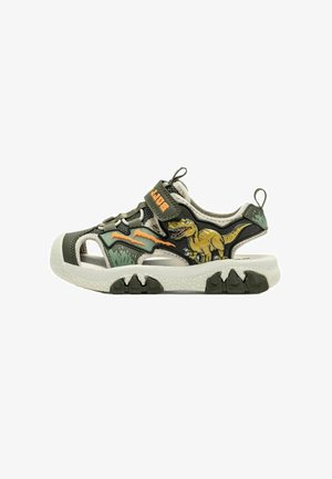Sandalo verde e beige per bambini con grafica di dinosauro e segni di artigli arancioni sul lato, con cinturino in velcro e suola spessa e strutturata.