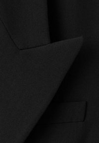 Czarne tkanina na zbliżeniu marynarki garniturowej, z eleganckim klapą, teksturowaną powierzchnią i pojedynczą kieszenią z przodu.