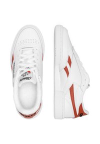 Adidași din piele albă cu accente roșii, cutie perforată pentru degete și șireturi contradictorii. Tălpi din cauciuc durabil cu branding pe călcâi.