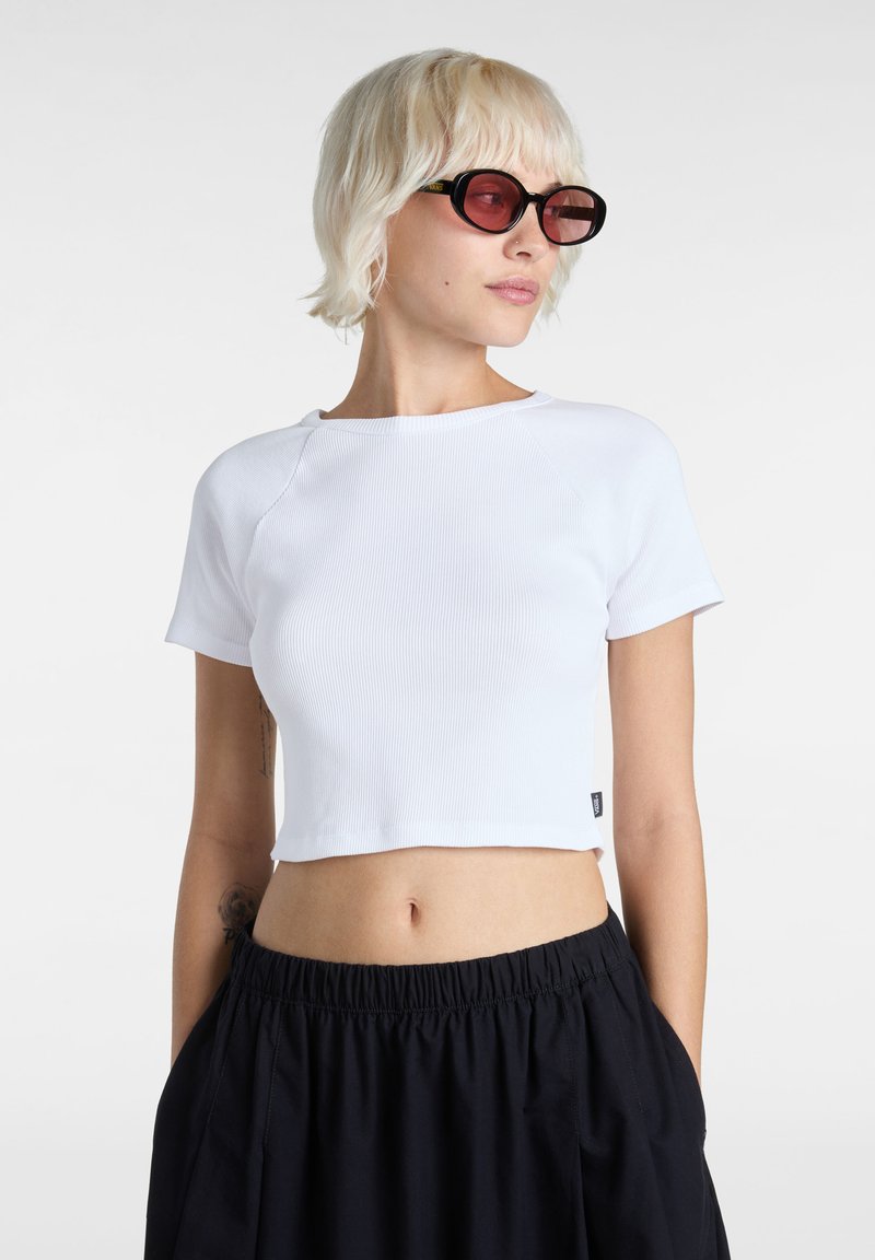 Top corto blanco acanalado con cuello redondo y mangas cortas raglán, combinado con pantalones negros holgados con una cintura elástica.