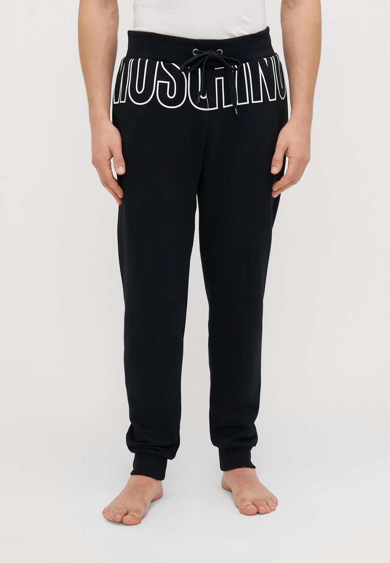 Melni sporta bikses, izgatavotas no kokvilnas maisījuma, ar balto "MOSCHINO" logotipa druku, elastīgu jostasvietu ar auklu un ribotām piedurknēm.