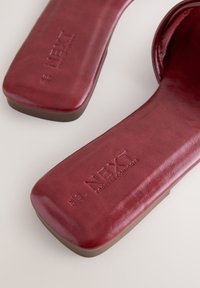 Sandales plates rouges avec bouts carrés et semelles intérieures rembourrées embossées du logo "NEXT Forever Comfort".