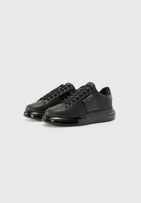 Sneaker in pelle nera con suola nera lucida. Presenta una superficie strutturata, design con lacci e marchio sul lato. Forma della punta rotonda.