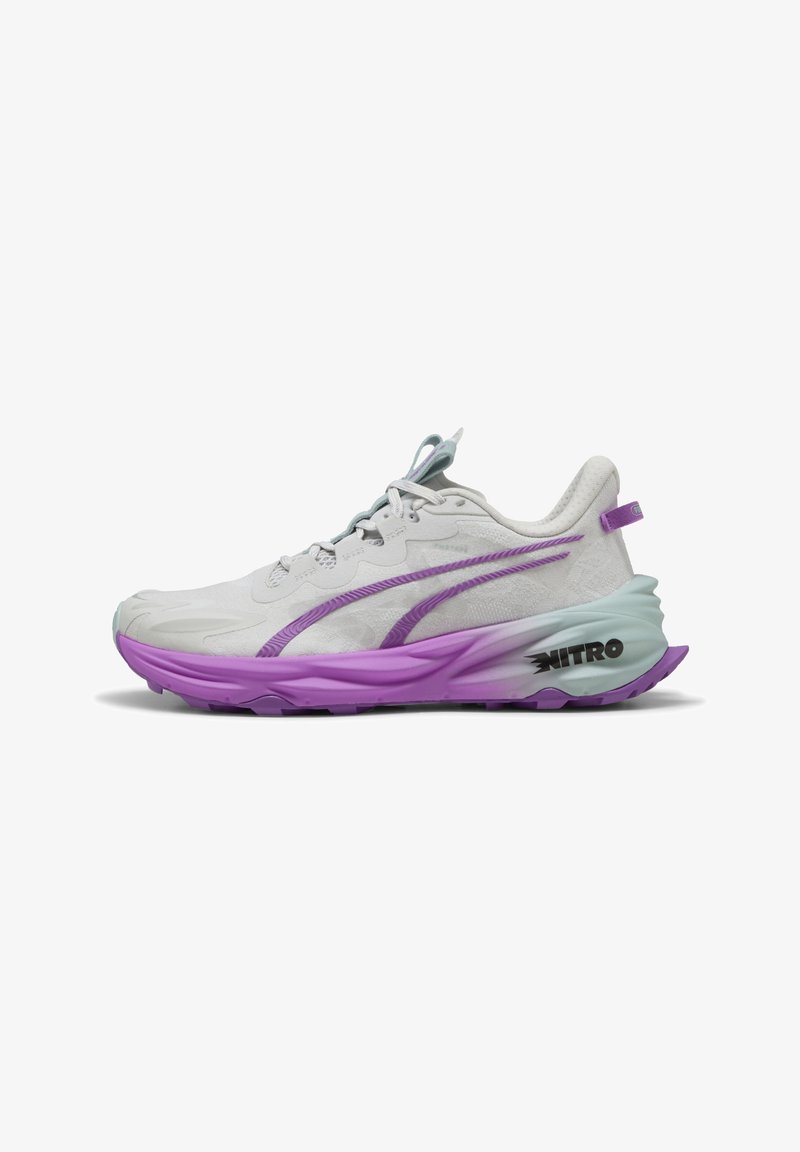 Scarpa da corsa leggera con una tomaia grigia, dettagli viola e una suola testurizzata. Presenta un'intersuola ammortizzata e un dettaglio sul tallone con logo.