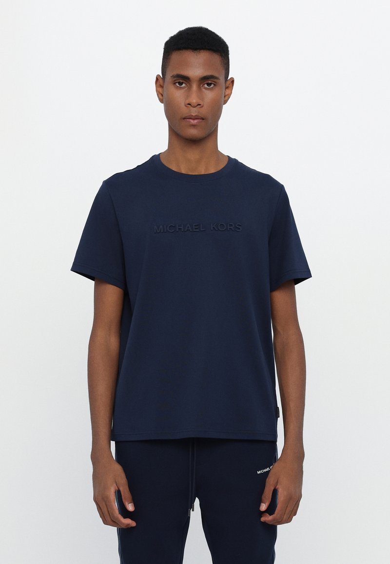 Mørkeblå bomulls T-skjorte med rund hals og korte ermer, med en subtil preget "MICHAEL KORS"-logo på forsiden.