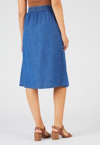 Falda midi de mezclilla con cintura elástica, en un tono azul medio, que presenta una silueta acampanada y un acabado de dobladillo simple.