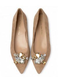 Ballerine beige in suede con punta appuntita e un'applicazione decorativa di gemme frontale, con pietre chiare e ambra. Interno in pelle liscia.