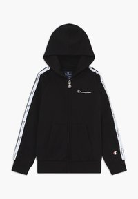 Felpa nera con zip e logo Champion bianco sul petto e sulle maniche, striscia bianca con loghi ripetuti lungo le braccia, tasche frontali e cappuccio.