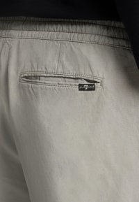 Shorts gris clair en tissu doux, dotés d'une taille élastique et d'une poche arrière avec une étiquette de marque cousue.