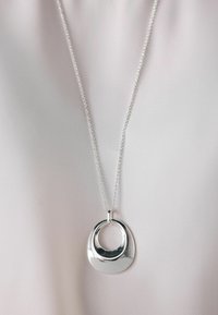 Silverhänge med en design av två cirklar, fäst vid en delikat kedja. Slät, glänsande yta med en polerad finish.
