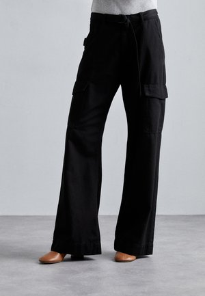Pantalon cargo noir en coton avec une coupe ample, doté de deux poches latérales et d'une ceinture à nouer. Texture douce, design à jambes larges.
