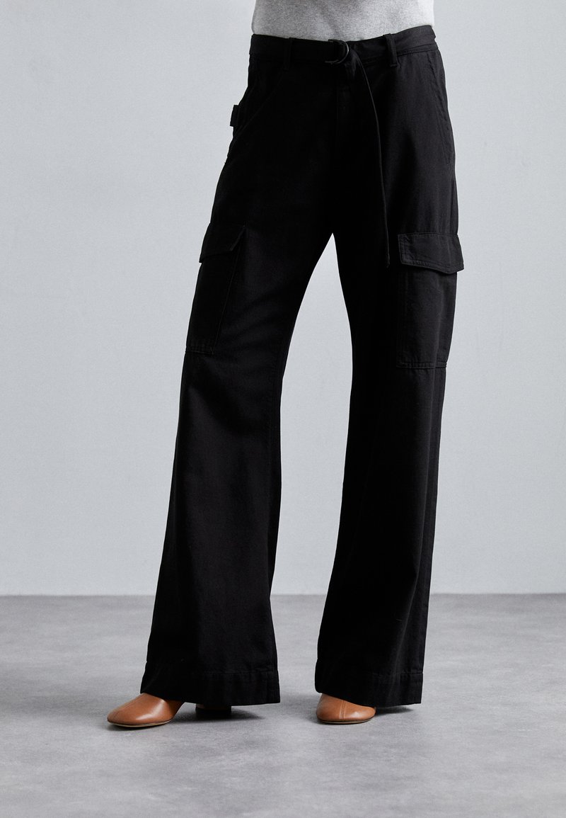 Black cargo pants made of cotton with a loose fit, featuring two side pockets and a tie waistband. Smooth texture, wide-leg design.
