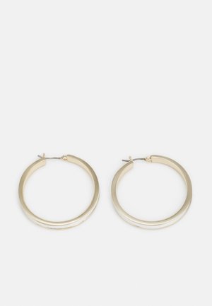 Par de pendientes de aro dorados medianos y brillantes con un diseño simple curvado y cierres de poste metálico sobre un fondo blanco liso.