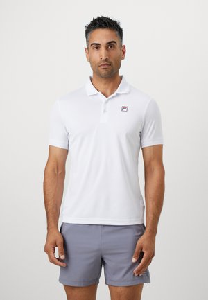 Hvit kortermet polo med krage og en liten logo på venstre bryst. Glatt stoff, tettsittende design, kombinert med grå shorts.