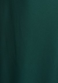 Temno zelena tkanina z gladko teksturo in rahlim sijajem; brez vzorcev ali opaznih podrobnosti. Enotna in homogena vidna podoba.