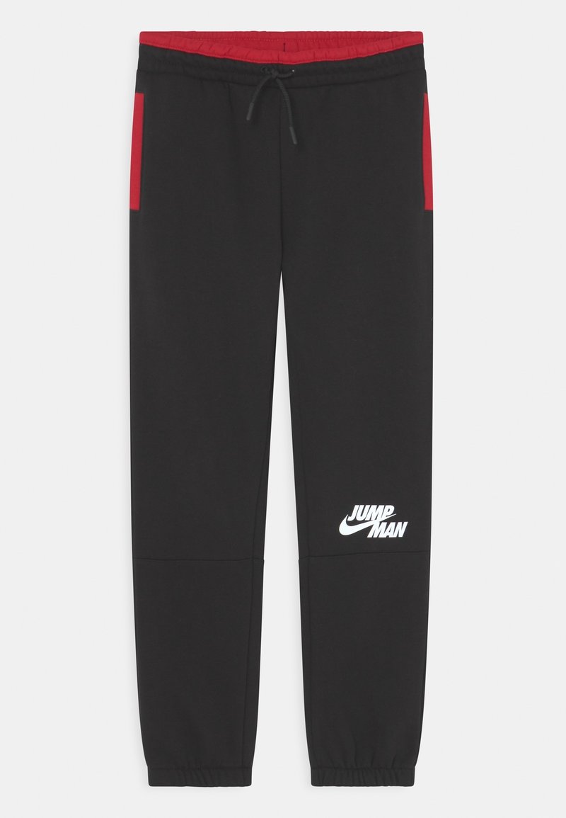 Schwarze Jogginghose mit roten Seitenelementen. Sie verfügt über einen elastischen Bund, eine verstellbare Kordel und ein weißes "Jumpman"-Logo am linken Bein.