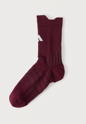 Chaussette de sport bordeaux unique avec texture côtelée, semelle rembourrée et une petite bande blanche en biais près de la cheville, présentée sur un fond uni.
