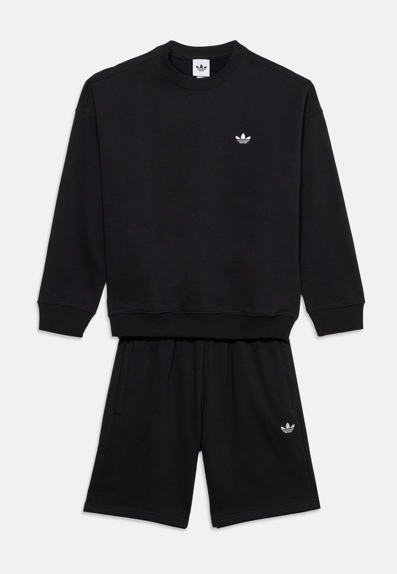 Черна суитшърт Adidas с кръгло деколте и черни къси панталони в същия цвят, и двете с малки бели лога на Adidas trefoil.