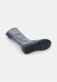 Botas altas de cuero negro con suela de goma gruesa y estriada, con cremallera lateral, mostradas de lado sobre un fondo blanco.