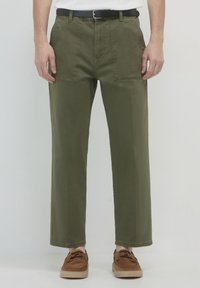 Olivgrüne Baumwollhosen mit geradem Bein, ausgestattet mit zweiFronttaschen und einem schwarzen Gürtel zum Schließen.