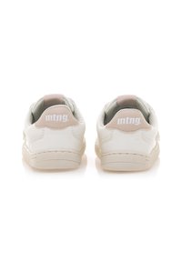 Zapatillas blancas con una textura suave, que cuentan con un tirador en el talón de color rosa claro y un logo, todo en un diseño minimalista con una suela de color crema.
