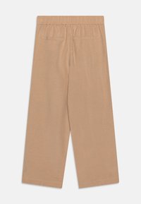 Pantalons larges beige avec taille élastique, deux poches arrière, texture douce et coupe ample. Tissu lisse avec un éclat subtil.