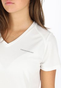 Hvid v-hals t-shirt lavet af letvægts tekstureret stof, med et lille "SWEDEMOUNT" logo på venstre brystområde. Korte ærmer.