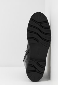 Czarny boot z teksturowaną skórzaną cholewą i wzorzystą gumową podeszwą, z boku zamkiem błyskawicznym oraz wytłoczonym detalem z logo.