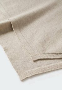 Écharpe en laine beige avec une texture douce, dotée d'un bord ourlé et d'une finition lisse. Le matériau est léger et tombe gracieusement.