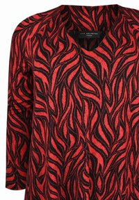 Top in tessuto nero con un motivo a foglie rosse, design a V, e maniche lunghe. Texture liscia con una vestibilità casual adatta a diverse occasioni.