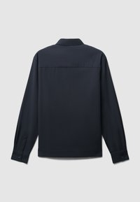 Camicetta a maniche lunghe di un blu navy scuro, realizzata in tessuto morbido, con colletto classico, polsini con bottone e un design semplice sul retro.