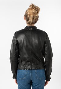 Zwarte leren jas met een relaxte pasvorm, gathered hem en hoge kraag. Gladde textuur, subtiele glans en elastische manchetten.