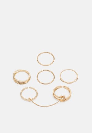 Set of five gold rings, varying in design: smooth bands, one with a chain link, and another with surface embellishments and stones.