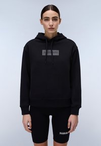 Svart hettegenser med cropped design, myk stoff og logopatch på brystet; paret med svarte sykkelshorts med logodetalj.