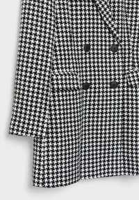 Blazer croisé à motif pied-de-poule noir et blanc avec boutons noirs et poches à rabat sur le devant.