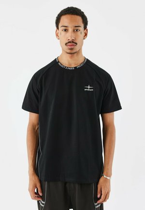 Camiseta negra de manga corta con diseño de raglán, que presenta un cuello redondo con el texto "PROJECT X PARIS" y un logo en el pecho. Acabado de tela suave.