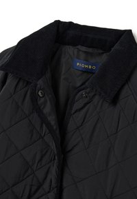 Giacca nera trapuntata con colletto in corduroy e bottoni a pressione, che mostra l'etichetta interna con il nome del brand "PIOMBO."
