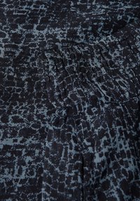 Dunkelblaues, strukturiertes Gewebe mit einem marmorierten Muster in helleren Blautönen und gerafften Details. Glatte Textur und flexibles Design.